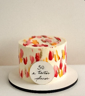 Bolo de buttercream branco com pinceladas em vermelho, rosa e laranja e uma plaquinha escrita à mão